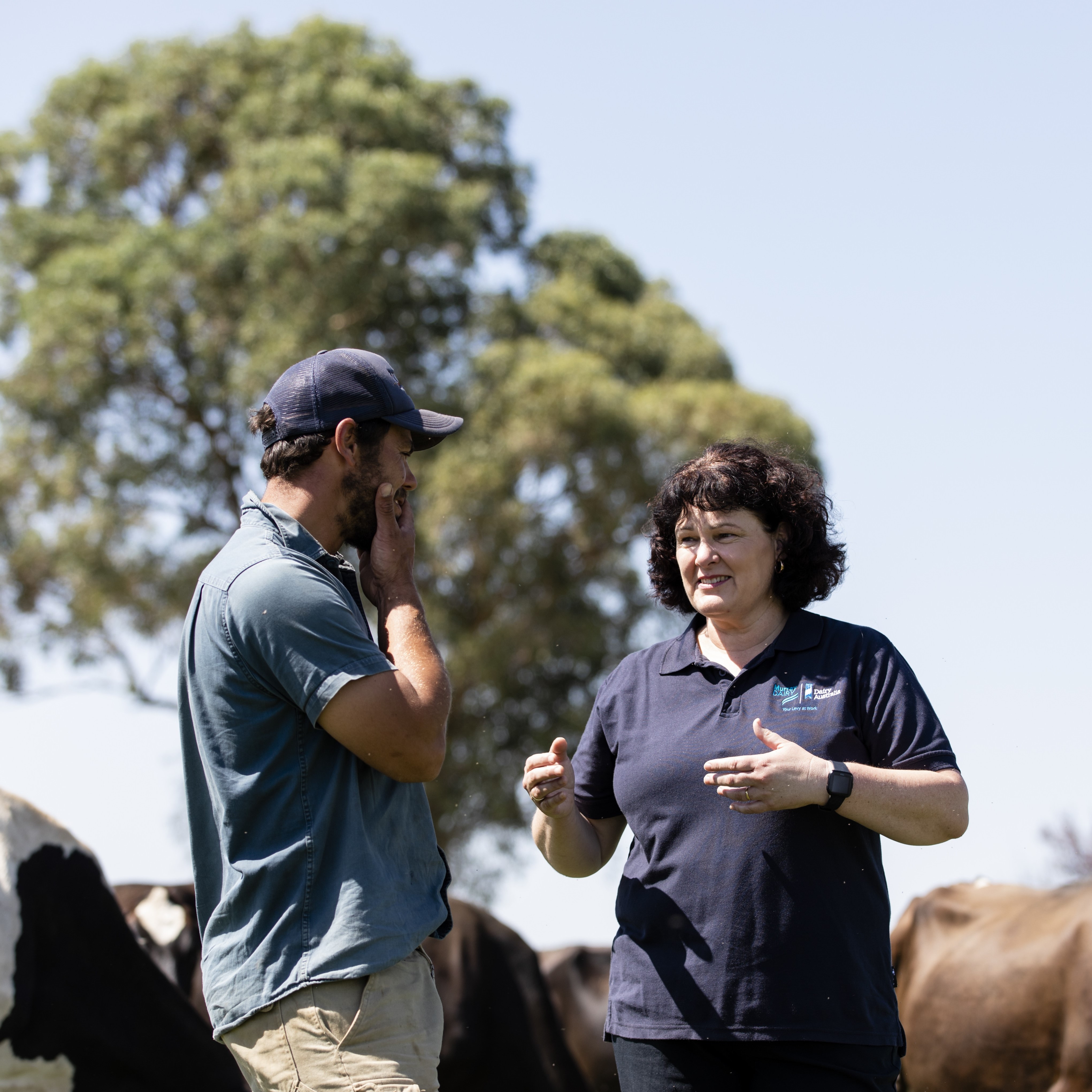 Melva Tyson with a farmer on a pasture, with cows in the background.